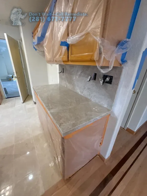 New stone countertop and backsplash, cabinets wrapped in plastic while the floor work finishes